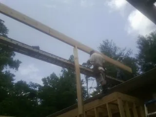 Carpenter setting a ridge beam over a new addition frame — Ice Dam Removal by Roofing Brothers in Dahinda