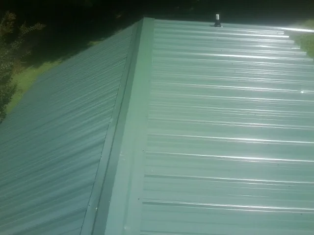 New green metal panels meeting at the ridge of a roof — Flat Roof Repair work by our crew in Dahinda