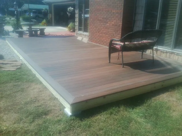 New wood deck and wicker chair beside a brick house in Dahinda