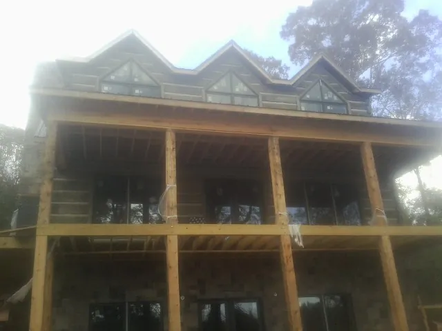 Dormers and porch framing on a large log home under construction — Roof Coating work by our crew in Dahinda