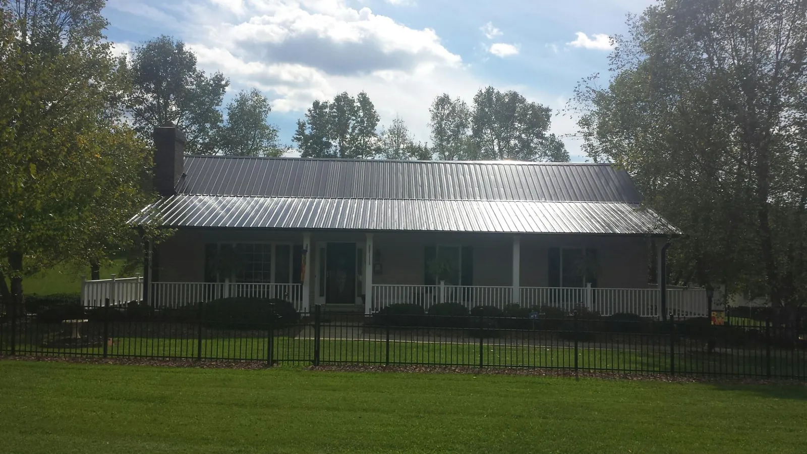 Gray metal roof on a brick ranch with a full width front porch — Gutter Guard Installation work by our crew in Dahinda