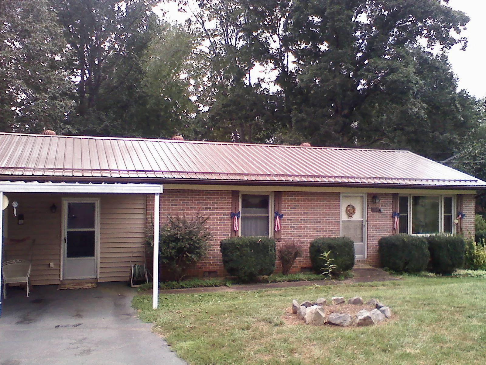 Bronze metal roof and carport on a brick ranch home — Roof Repair work by our crew in Dahinda