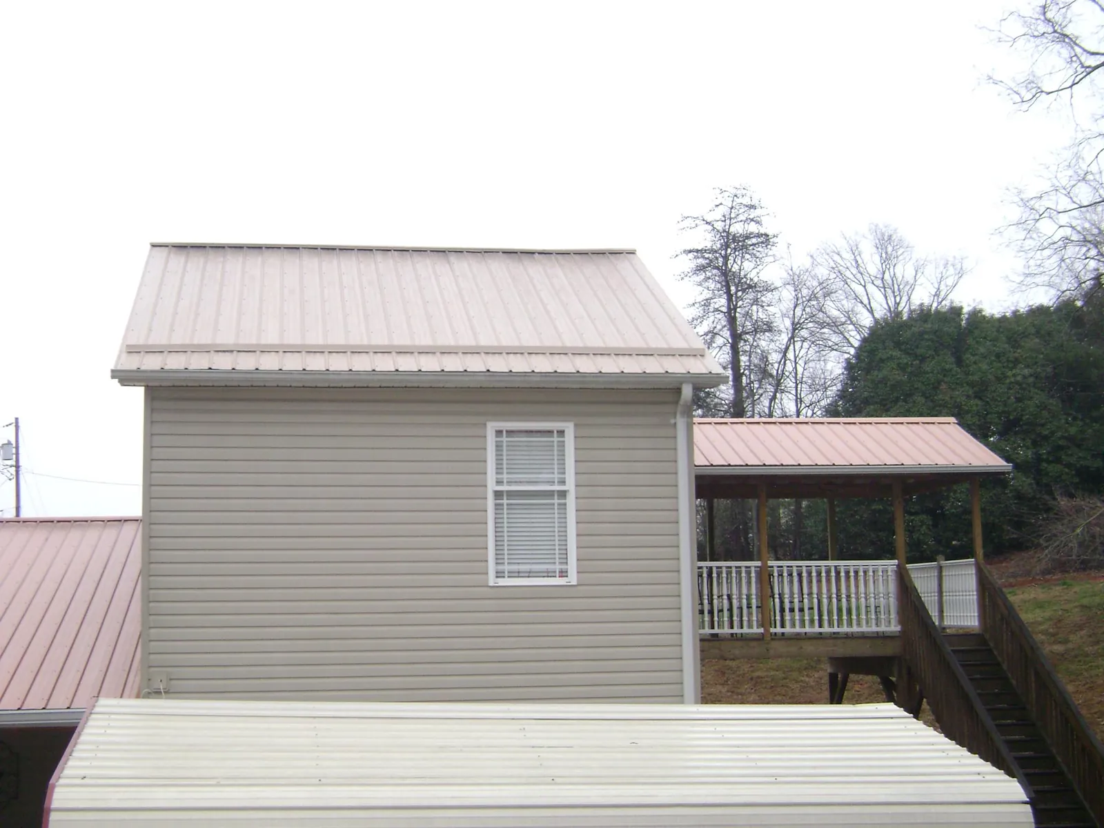 Tan metal roofs on a two story addition and attached porch, from a Roof Replacement job in Dahinda