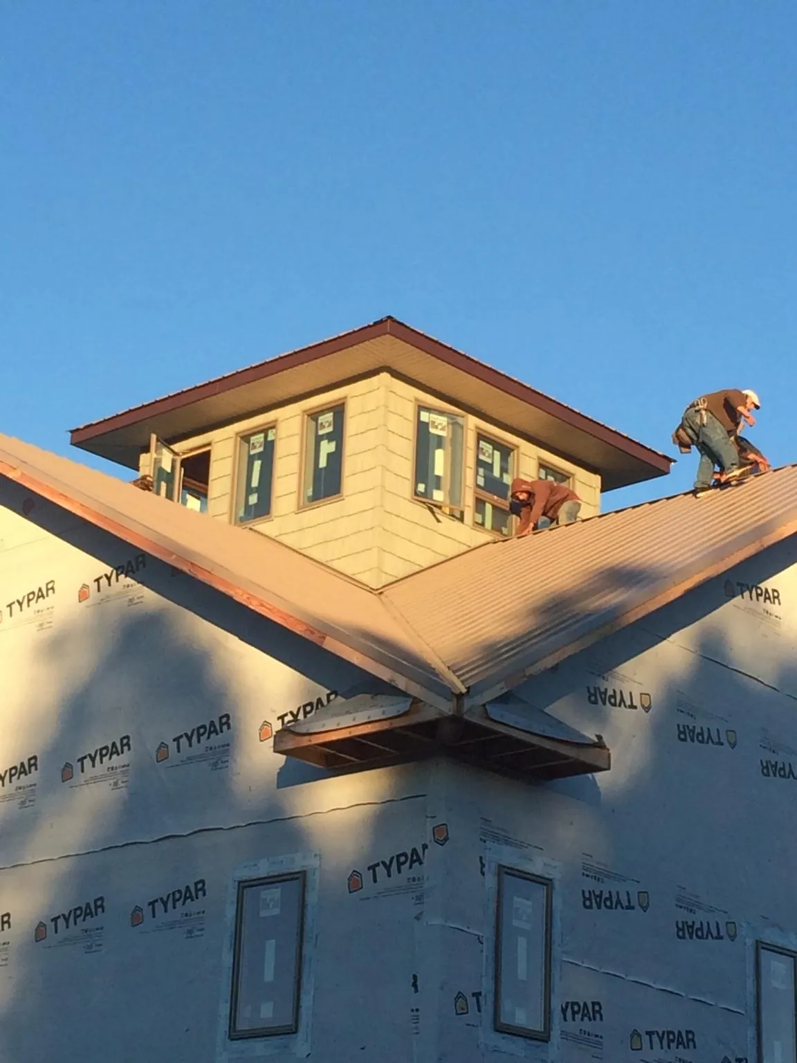 Roofers working around a rooftop cupola on a new metal roof at sunset — Roof Waterproofing in Dahinda by Roofing Brothers